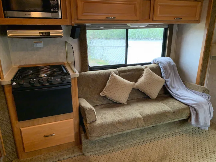 Cozy RV rental interior featuring a full kitchen with microwave, stove, and a comfy sofa for travel and relaxation.. Tioga M-30u Ford 2005