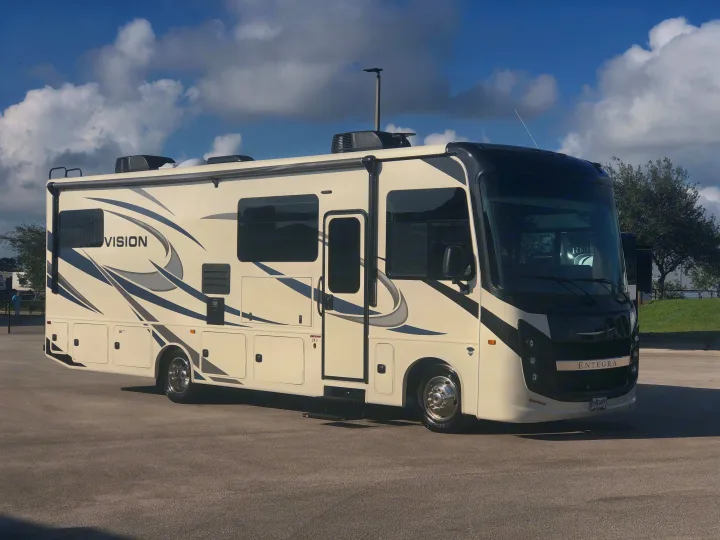 Sleek cream & black Entegra Vision RV motorhome parked on asphalt under blue sky. Perfect for your rv rental adventure.. Entegra Coach Other 2021