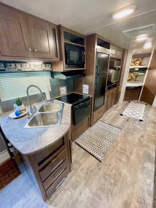 Cozy RV rental interior with full kitchen (sink, stove, fridge, microwave), light wood floors & bunk beds.. Heartland Pioneer 2018