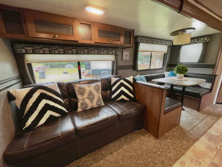 Cozy RV rental interior showcasing a comfortable leather sofa, stylish pillows, and a practical dinette for travelers.. Heartland Pioneer 2018