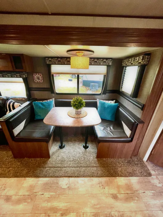 Cozy RV rental dinette features dark booths, a central table, and outdoor views through large windows.. Heartland Pioneer 2018