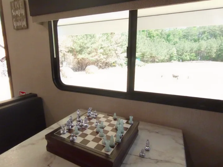 Glass chess set on a table in a cozy RV rental. Relax and enjoy the scenic view outside this peaceful space.. KZ Sportsmen 2021