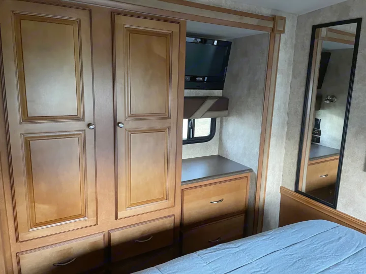 RV rental's cozy interior: wooden cabinets, mirror, and TV setup in a compact living space.. Itasca Sunstar 2012