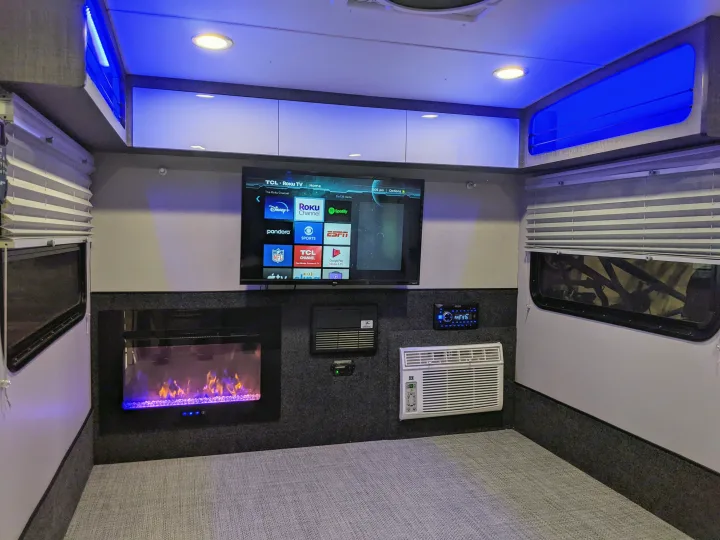 This modern rv rental interior features a TCL Roku TV, electric fireplace, AC unit, and ambient blue lighting for comfortable travel.. InTech RV InTech RV Trailer 2021