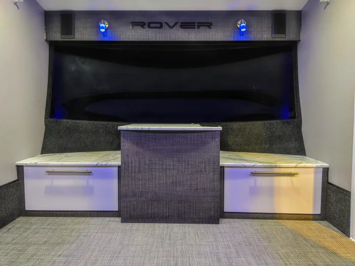 RV rental interior featuring a modern entertainment area with a large dark screen, "ROVER" branding, blue lights, and white/grey cabinets.. InTech RV InTech RV Trailer 2021