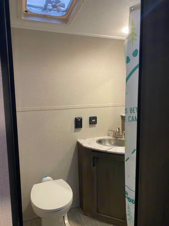 Experience an RV rental bathroom! Features a compact toilet, sink, vanity, and a nature-themed shower curtain.. Sonic Lite 2021