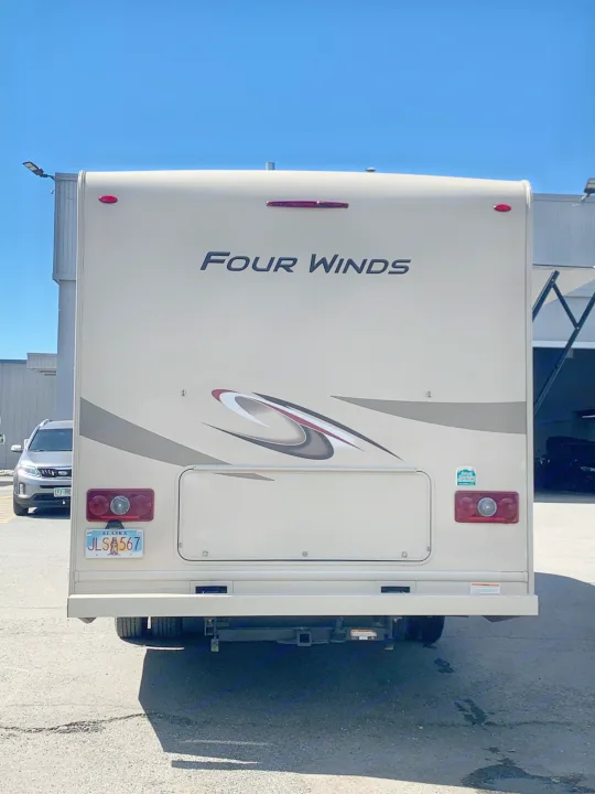 Rear view of a beige Four Winds RV, great for an RV rental. Visible features include taillights and an Alaska license plate.. Thor Motor Coach Four Winds 2019