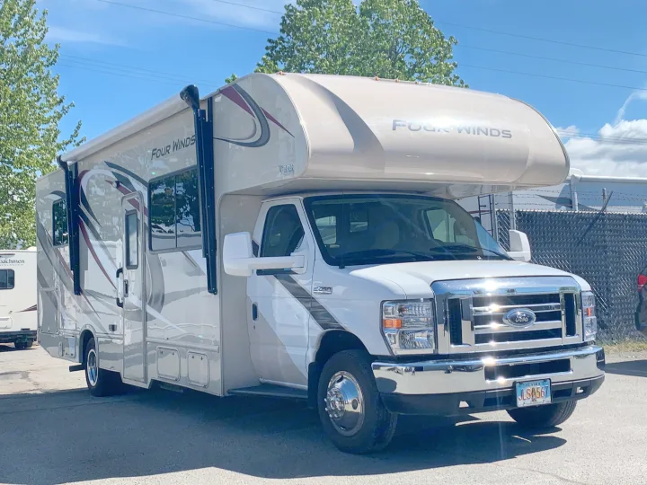 Spacious white and tan Four Winds Class C RV rental, a Ford E450 recreational vehicle parked outdoors, ready for adventure.. Thor Motor Coach Four Winds 2019