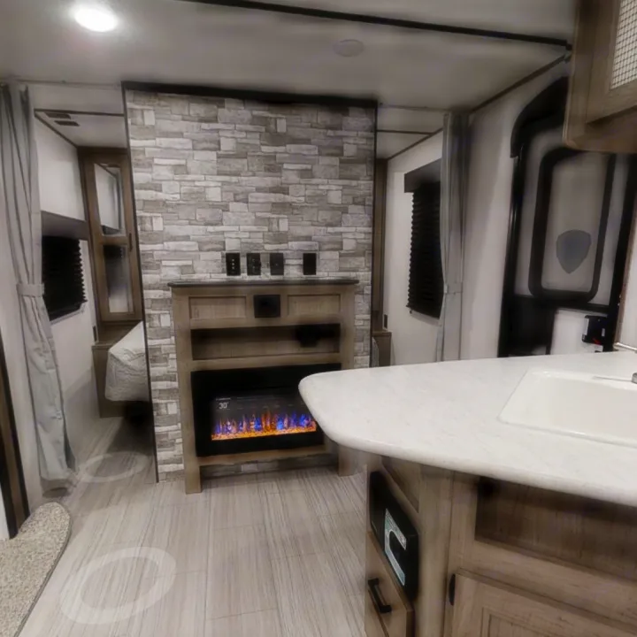Step inside this modern RV rental, featuring a cozy electric fireplace, full kitchen, and spacious bedroom area.. Keystone Hideout 2021