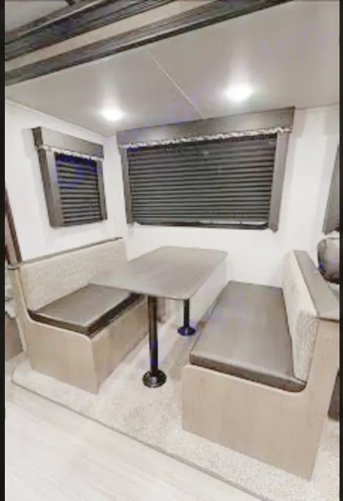 Cozy RV rental dinette setup, perfect for dining on your next travel adventure. Features modern decor and blinds.. Keystone Hideout 2021