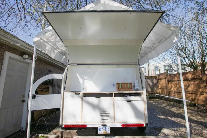 Teardrop RV rental: Rear view of a compact camper's open kitchen galley with sink, stove, and storage drawers.. Droplet Teardrop 2020