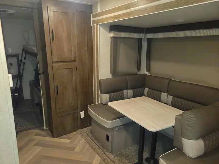 Spacious RV rental interior with U-shaped dinette, bunk beds, and wood-look cabinetry. Ideal for family travel.. Forest River Salem 2021