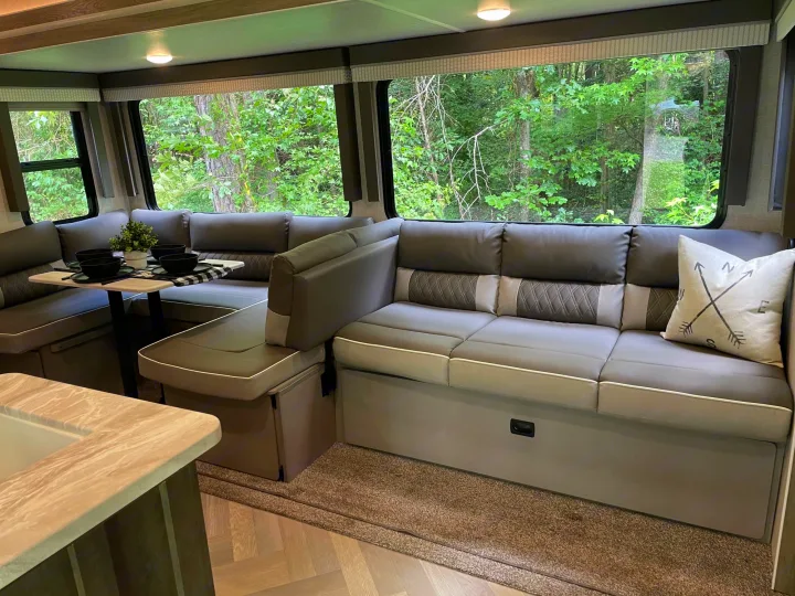 RV rental living area: A large sectional sofa/dinette with a set table, offering lush forest views from wide windows.. Forest River Salem 2021