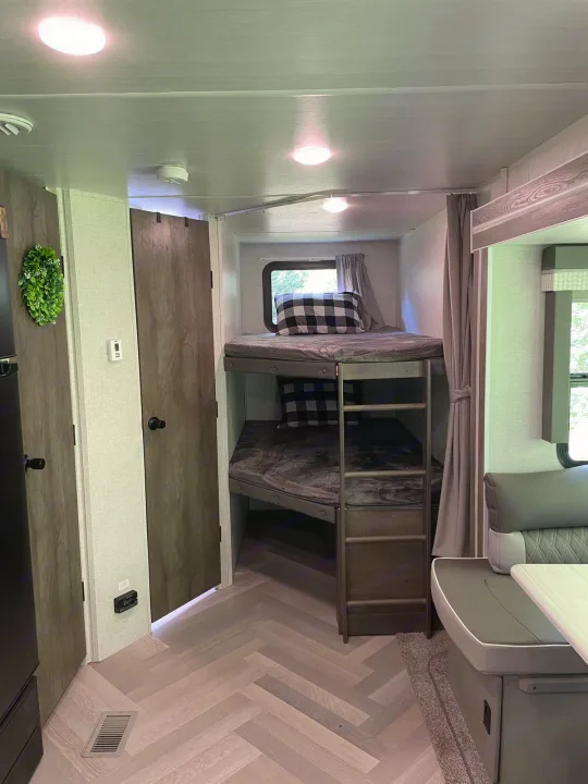 Spacious RV rental interior with comfortable bunk beds, dining area, and stylish herringbone flooring. Perfect camper for families!. Forest River Salem 2021
