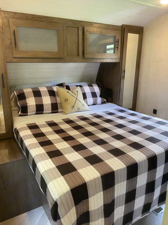 RV rental bedroom with cozy plaid bedding, overhead cabinets, and built-in storage. Perfect for your next adventure.. Forest River Salem 2021