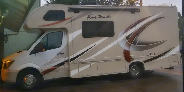 This beige Four Winds Class C motorhome RV rental, featuring a sleek design, is parked and ready for adventures.. Mercedes Benz Four Winds 2018