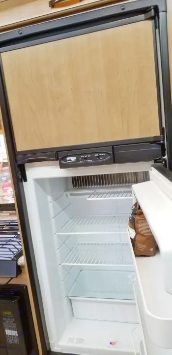 Explore this RV rental's kitchen, featuring an open Norcold refrigerator with adjustable shelves and intuitive controls.. Mercedes Benz Four Winds 2018