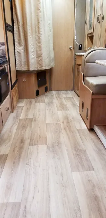 Inside an **rv rental**, a clean view of light wood-look flooring, beige dinette, and kitchen area, ready for travel.. Mercedes Benz Four Winds 2018