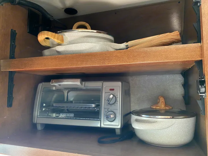 Efficient RV rental kitchen storage with a Black+Decker toaster oven and cookware neatly stored on shelves.. Winnebago Porto 2020