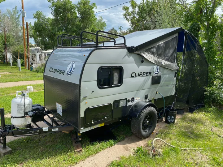 This gray Clipper pop-up camping trailer is perfect for RV rental getaways, featuring a raised roof and rugged tires.. Coachmen Clipper 2021