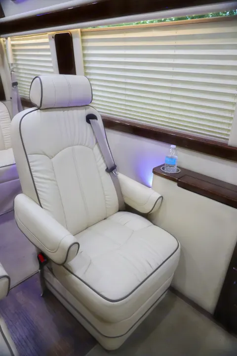 Plush white leather captain's chair inside a luxurious rv rental, featuring a seatbelt and ambient lighting for comfortable travel.. Mercedes 3500 2018