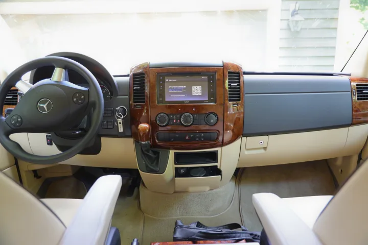 Spacious Mercedes-Benz RV rental interior, showing the dashboard, steering wheel, and infotainment system with Auto+ Connect app info.. Mercedes 3500 2018