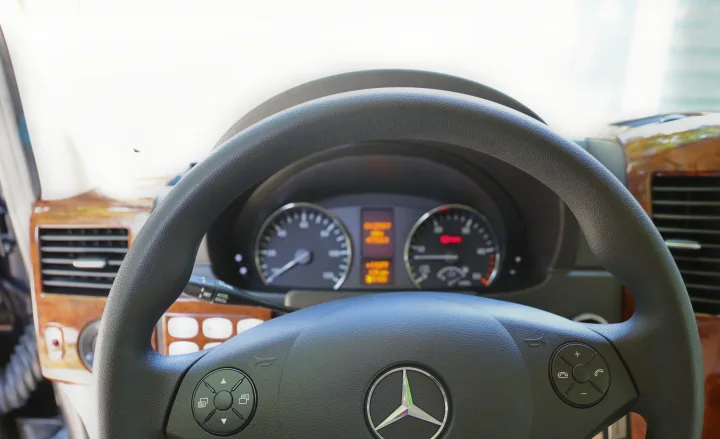Driver's view of a Mercedes-Benz RV rental interior, showing the steering wheel, dashboard, and controls.. Mercedes 3500 2018