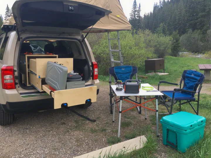 Overland RV rental setup: SUV with rooftop tent, pull-out kitchen, and full campsite furniture ready for adventure.. Jeep Patriot 2016