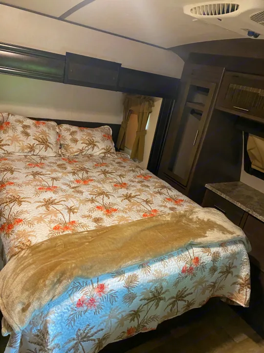 Cozy RV rental bedroom with tropical palm tree bedding & built-in storage. Ideal for a comfortable adventure!. Crossroads Sunset Trail Reserve 2018