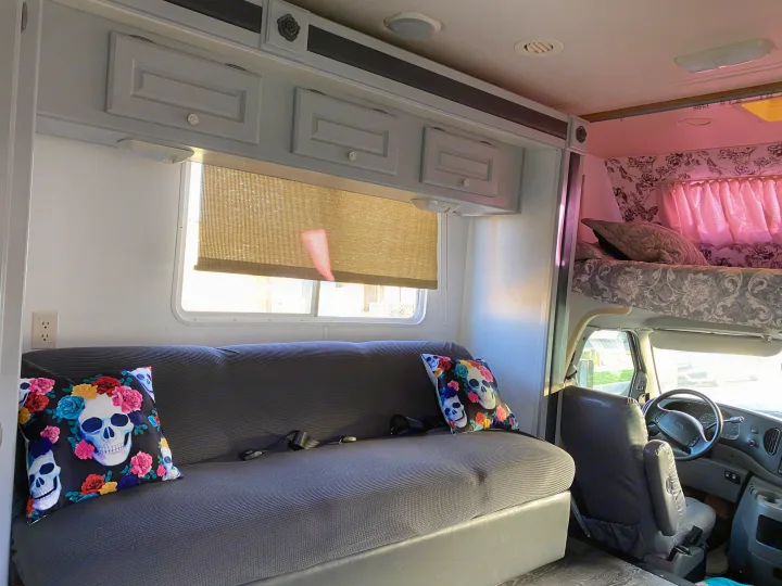 Patterned sofa with skull pillows, overhead cabinets, and a bunk bed are seen inside this cozy RV rental.. Holiday Rambler Atlantis 2002