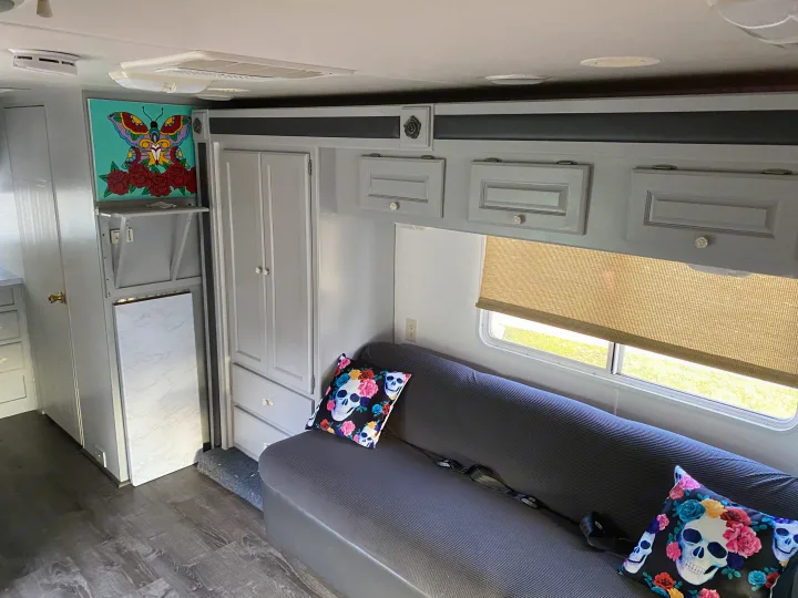 RV rental: Gray camper living area with skull pillows, butterfly art, and a window with a blind.. Holiday Rambler Atlantis 2002