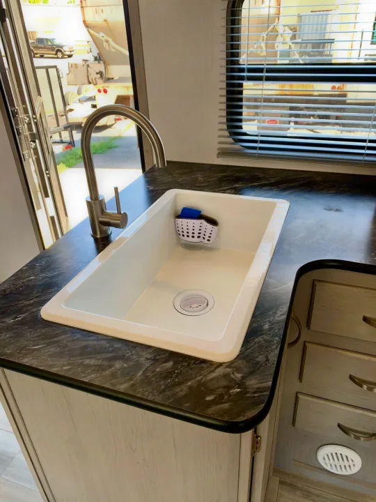 Clean, modern RV rental kitchen featuring a white sink, sleek faucet, and dark marbled counter. Spacious and ready for use.. Forest River Tracer 260BHSLE 2021