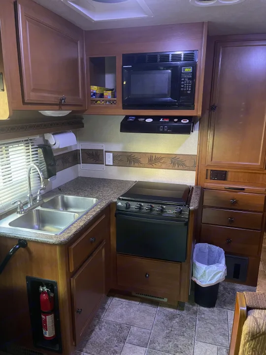 RV rental kitchen interior, showcasing a double sink, microwave, and stove, with ample cabinets and drawers for storage.. Other Other 2010