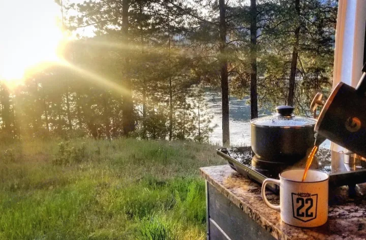 Serene RV rental morning: coffee pouring into a mug on a counter, overlooking a sun-drenched river & trees.. Dodge Ram Promaster 2500 2019