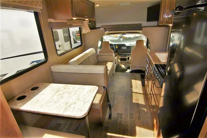 Explore this RV rental's spacious interior: comfortable dinette, functional kitchen, and front cockpit. Ready for adventure.. Winnebago Outlook 2019
