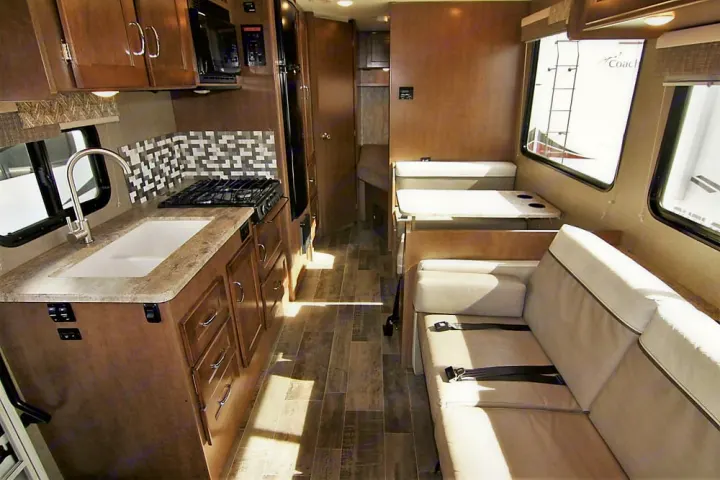 This rv rental shows its full interior: kitchen with sink/stove on left, central aisle, dinette, and sofa seating on right.. Winnebago Outlook 2019