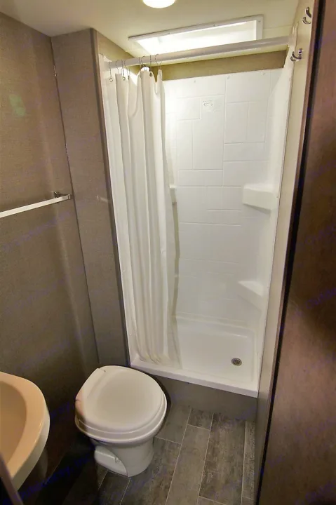 RV rental bathroom: A clean, compact space with a white shower, toilet, and small sink for comfortable travel.. Winnebago Outlook 2019