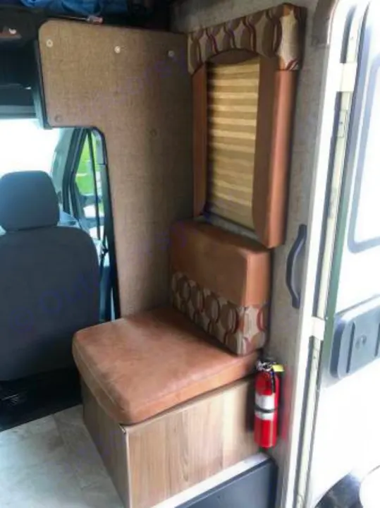 Compact RV rental interior showing brown seating, window blinds, and a fire extinguisher for safety.. Coachmen Freelander 2018