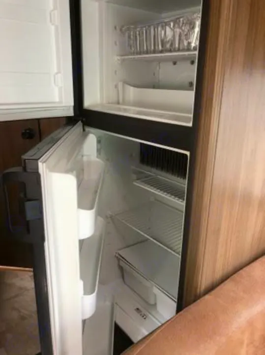 Inside a clean, empty RV rental refrigerator and freezer, complete with shelves, ready for your vacation essentials.. Coachmen Freelander 2018