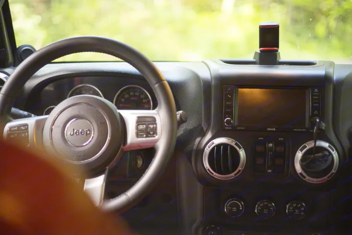 View from inside a Jeep. The steering wheel, dashboard, and infotainment screen are visible, perfect for an RV rental trip.. Jeep Wrangler Unlimited Rubicon 4x4 2013