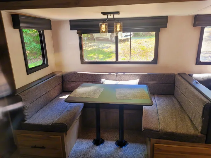 Modern RV rental dinette featuring comfortable grey U-shaped seating and ample windows for views.. Forest River Cherokee Alpha Wolf 2021
