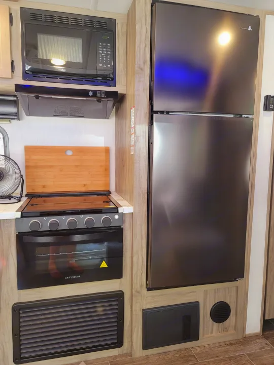 Modern RV rental kitchen featuring microwave, oven, and large fridge. Ideal for your next adventure!. Forest River Cherokee Alpha Wolf 2021