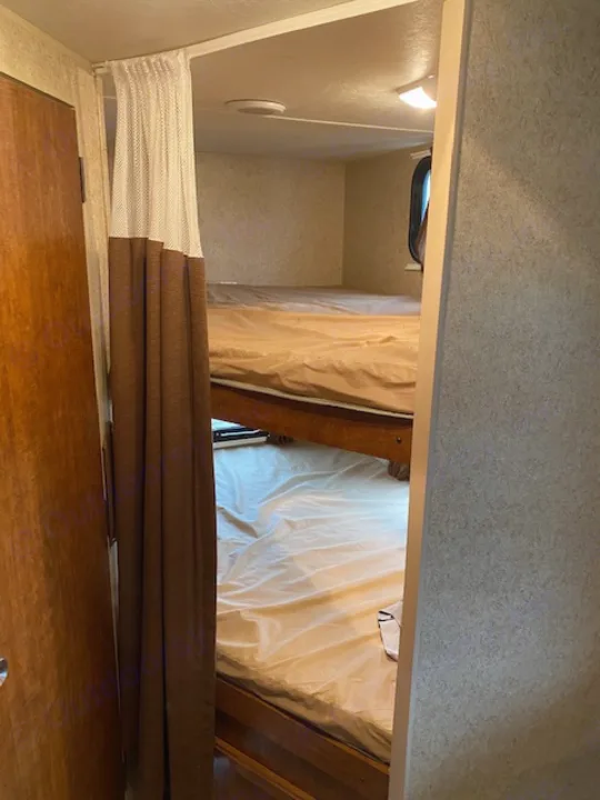 Explore this RV rental's over-cab bunk bed, featuring a safety net, light, and window for a compact sleeping area.. Skyline NOMAD Joey Select 292 BHS  Double Wide Bunk 2014