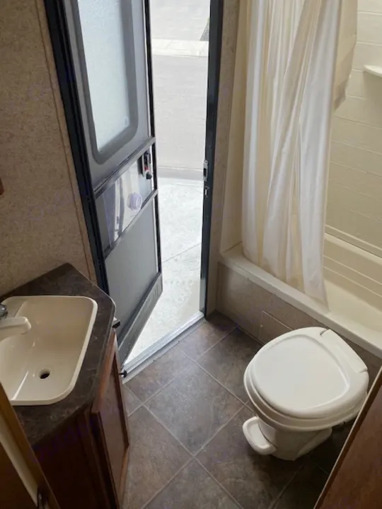 A clean and compact RV rental bathroom, featuring a toilet, sink, and shower curtain for your travels.. Skyline NOMAD Joey Select 292 BHS  Double Wide Bunk 2014