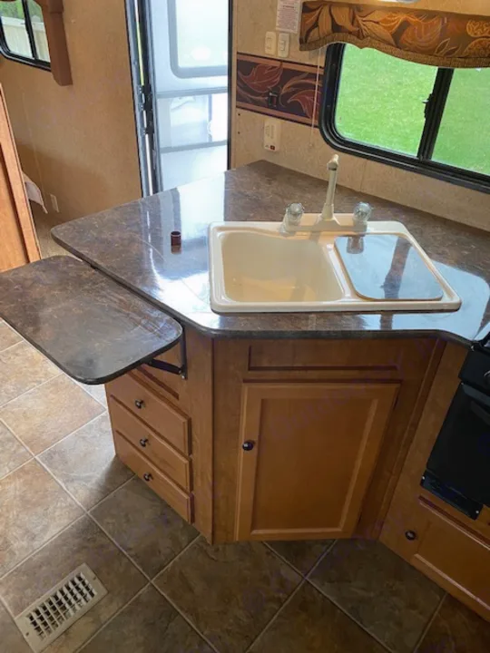 RV rental interior: Kitchenette with a sink, faucet, and wood cabinets. Tiled floor and windows offer an outside view.. Skyline NOMAD Joey Select 292 BHS  Double Wide Bunk 2014