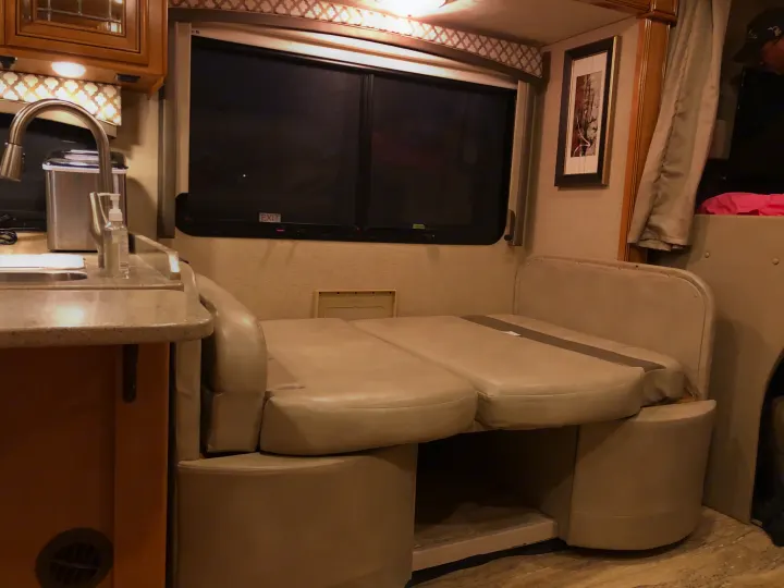 An RV rental interior with a kitchen sink, overhead cabinets, and a versatile dinette converting to a bed.. Thor Chateau 2017