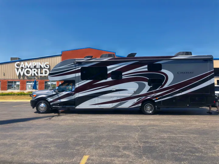 A Class C Thor Motor Coach Chateau RV with distinctive grey and maroon graphics at a Camping World location, perfect for RV rental.. Thor Chateau 2017