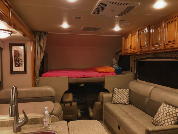 Inside a comfortable rv rental: A view of the bed, sofa, kitchen, and driver's area, showcasing the well-lit living space.. Thor Chateau 2017