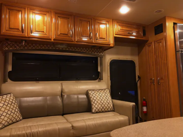 Cozy RV rental living space with a plush sofa, elegant wooden cabinets, and modern features for your travel comfort.. Thor Chateau 2017