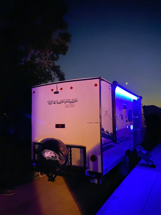 Experience outdoor adventure! This Forest River "Wolf Pup" RV rental glows with blue LEDs under a starry, moonlit sky.. Forest River Cherokee Wolf Pup 16PFBL 2021